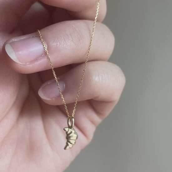 14k Yellow Gold Croissant Pendant dangling from hand