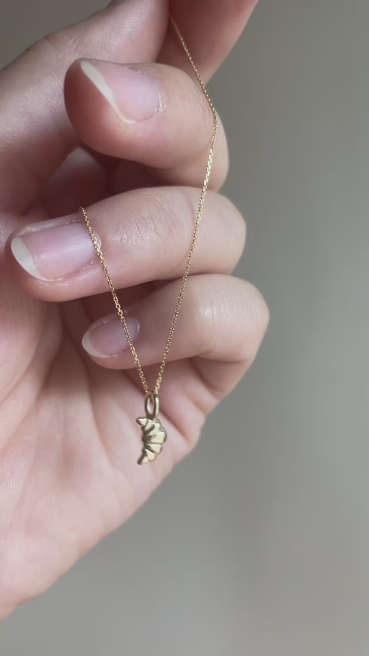 14k Yellow Gold Croissant Pendant dangling from hand